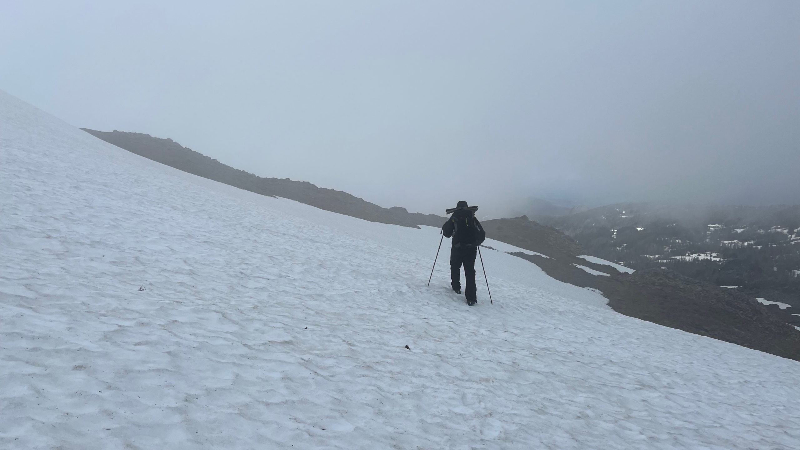 Backpacker crossing a snow field in the mountains